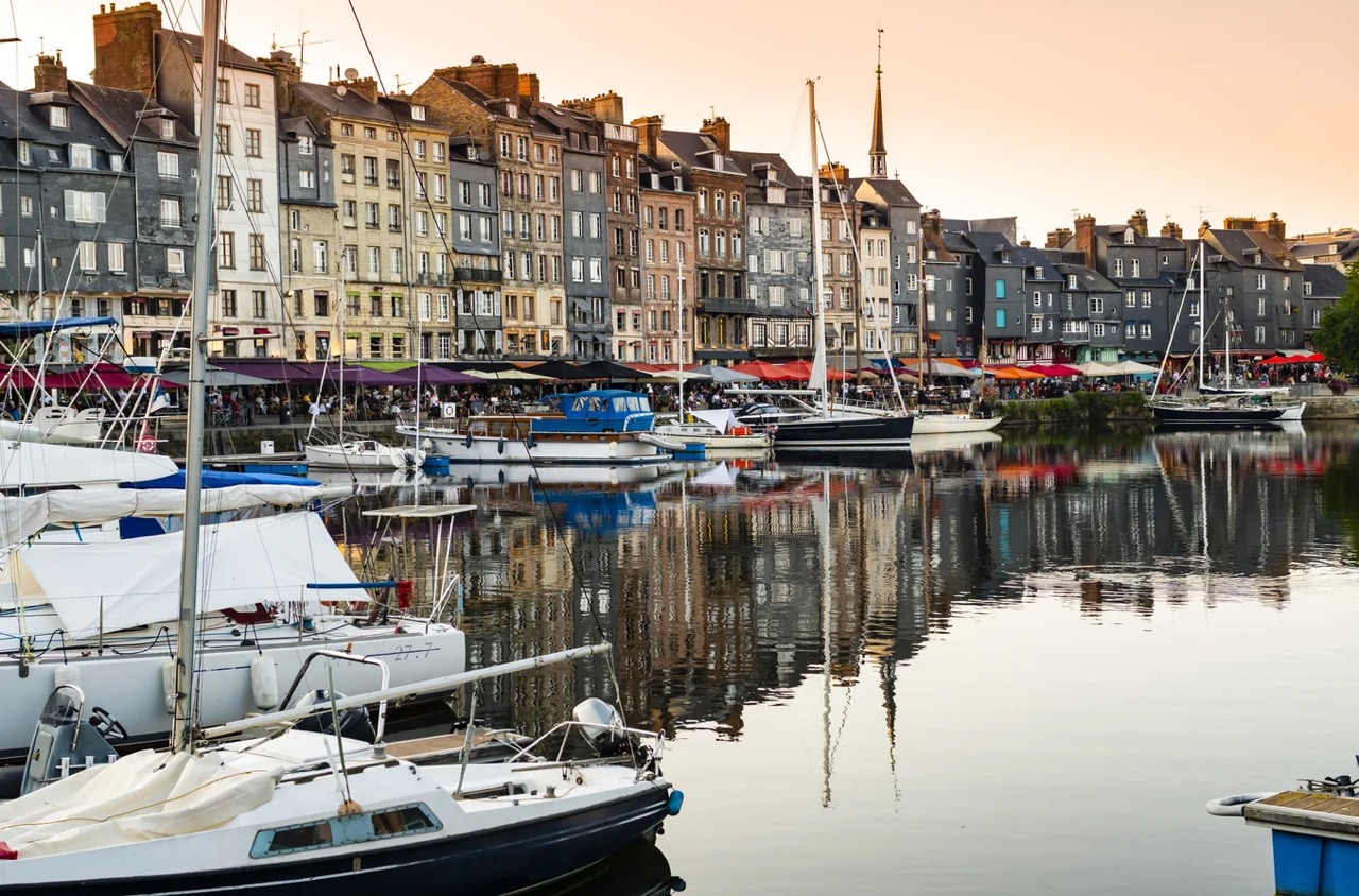 Vue du port de Honfleur au coucher du soleil, avec ses maisons colorées typiques de la Côte Fleurie et ses voiliers amarrés – Normandie, France.