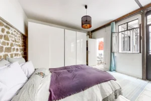 Chambre avec dressing intégré, grande fenêtre atelier et décoration sobre.