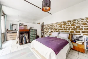 Mur en pierres naturelles, literie confortable et mobilier vintage.