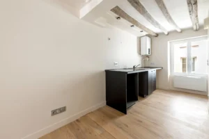 Cuisine ouverte à aménager, avec parquet clair et poutres apparentes, logement à réinventer Paris 11