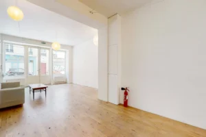 Espace bureau ou accueil dans un local professionnel situé à Paris 11ᵉ, avec murs blancs et sol parqueté.