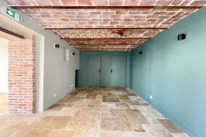 arrière boutique avec brique apparentes et plafond en briques, accès aux wc et à une réserve