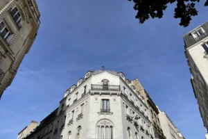 Vue en contre-plongée sur une façade élégante à Montmartre, ciel bleu en arrière-plan.