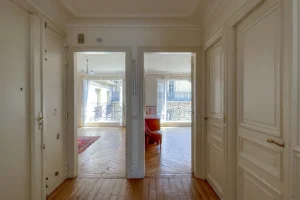 Vue depuis le couloir d’entrée sur deux chambres ouvertes côté rue, lumière naturelle omniprésente.