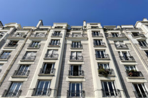 Façade en briques claires avec balcons en fer forgé d’un immeuble Art déco à Paris 16.