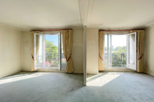 Salon lumineux avec double exposition, moulures et deux balcons dans un appartement à Paris 16.