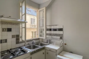 Cuisine avec évier double, placards anciens et vue dégagée sur cour intérieure, Paris 9 Conservatoire.