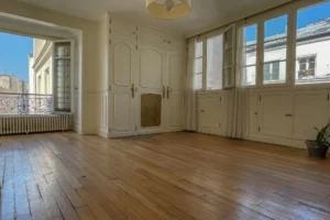 Pièce de vie traversante avec double exposition et parquet massif, idéal pour un aménagement chaleureux dans un immeuble ancien à Paris 9.