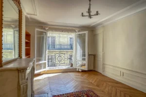 Chambre élégante avec moulures et parquet en point de Hongrie, ouvrant sur balcon filant typique du secteur Conservatoire.