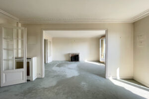Double séjour traversant avec cheminée ancienne et moulures dans un appartement haussmannien à Paris 16.