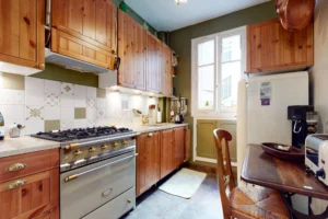 Cuisine traditionnelle avec crédence à motifs, gazinière vintage et mobilier en bois.