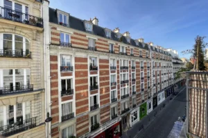 Façades en briques rouges et blanches d’un immeuble parisien typique dans une rue calme du 18ᵉ.