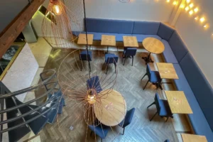 Vue en hauteur de la salle du local commercial restaurant à Paris 10 avec tables, banquettes et suspensions design