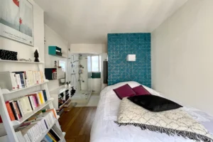 Chambre avec mur bleu graphique, accès direct à la salle d’eau, parquet ancien, Paris 18.