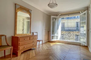 Seconde chambre avec grand miroir, dressing intégré et large ouverture sur balcon côté rue, Paris 9 secteur Cadet/Conservatoire.
