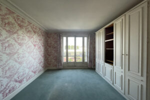Chambre avec grands placards intégrés et balcon offrant une vue dégagée dans un appartement à Paris 16.