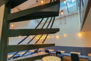 Vue de la salle du local commercial restaurant à Paris 10 à travers l’escalier hélicoïdal et la verrière