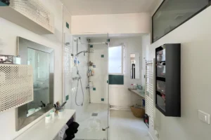 Salle d’eau moderne avec douche à l’italienne, vasque, rangements et lumière naturelle, Paris 18.