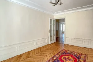 Vue sur une chambre avec moulures et hauteur sous plafond, parquet ancien conservé et lumière traversante.