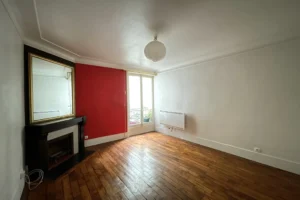 Grand séjour lumineux avec parquet ancien, moulures et cheminée en marbre.
