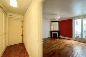 Entrée et séjour avec détail d’une cheminée noire surmontée d’un miroir doré dans un intérieur parisien classique.