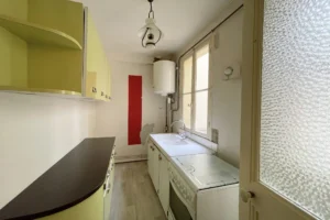 Cuisine indépendante à rénover, avec ballon d’eau chaude et meubles anciens.