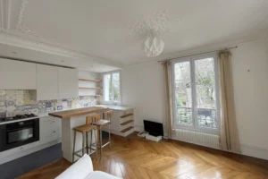 Cuisine américaine avec carreaux décoratifs, parquet haussmannien et vue dégagée sur la verdure à Montmartre, Paris 18ᵉ.