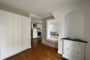 Entrée avec grands rangements intégrés et vue traversante sur le séjour et la cuisine d’un appartement à Montmartre, Paris 18ᵉ.
