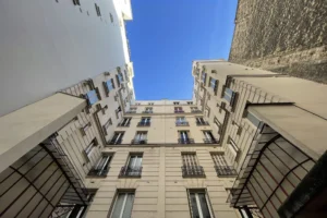 Façade intérieure de l’immeuble parisien avec fenêtres anciennes et balcons.