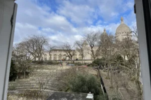 Vue exceptionnelle sur le Sacré-Cœur, les escaliers typiques et les Arènes de Montmartre depuis un appartement à vendre dans le 18ᵉ arrondissement de Paris.