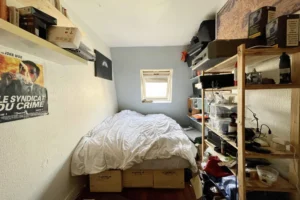 Chambre sous les toits avec lit double, rangements intégrés et bureau, dans un appartement à Montmartre, Paris 18e.