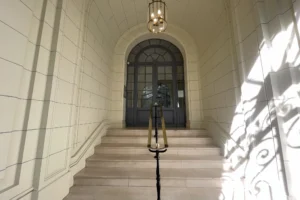 Hall d’entrée monumental d’un immeuble haussmannien à Paris 18e avec escalier en pierre, rampe en laiton et arche en plein centre.