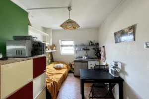 Pièce de vie d’un studio à Montmartre, Paris 18e, avec coin cuisine équipé, espace repas et coin nuit sous les toits.