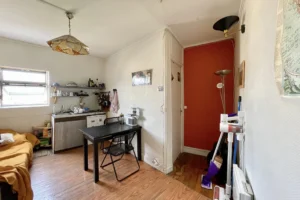 Studio fonctionnel à Paris 18e avec coin cuisine, espace repas et vue sur le couloir d’entrée, situé dans le quartier Montmartre.