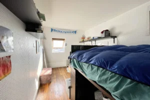 Chambre lumineuse avec lit en mezzanine, parquet ancien et rangements muraux, dans un appartement situé à Montmartre, Paris 18e.
