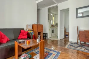Séjour avec parquet ancien et cuisine ouverte dans appartement à vendre Paris 10, secteur Faubourg Saint-Denis.
