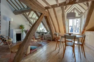 Vue principale du séjour sous les toits à vendre Paris 10, poutres apparentes et lumière naturelle – Quality Street Immobilier Faubourg Saint-Denis.