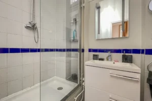 Salle d’eau avec douche vitrée et vasque moderne, faïence blanche et bleue, Paris 10.