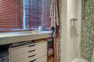 Salle d’eau avec douche italienne en mosaïque verte et rangements.