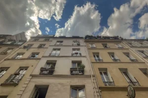 Façade sur rue typique du 10e arrondissement de Paris, ciel nuageux en arrière-plan.