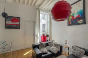 Espace salon cosy avec grande fenêtre sur cour et luminaires design, appartement Paris 10.