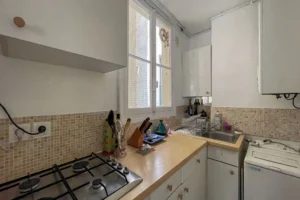Cuisine indépendante claire et fonctionnelle avec fenêtre, rangements et électroménager, dans un appartement à vendre à Paris 10ᵉ, quartier Faubourg Saint-Denis.