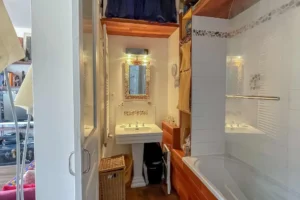 Salle de bains avec baignoire, lavabo sur colonne et rangements intégrés, espace fonctionnel et lumineux au sein d’un appartement situé rue du Faubourg Saint-Denis, secteur Gare du Nord à Paris 10.