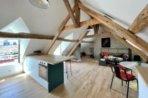 Appartement à vendre à Chantilly par Quality Street Immobilier, séjour sous combles avec poutres apparentes et lumière naturelle.