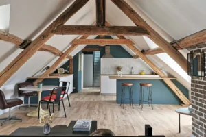 Séjour lumineux avec charpente ancienne, cuisine ouverte et parquet dans un appartement rénové à Chantilly.