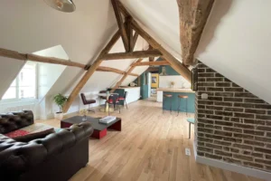 Salon cosy avec parquet bois, murs blancs et poutres anciennes dans appartement rénové à Chantilly.