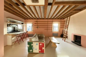 A vendre loft Paris 10 Bonne Nouvelle Quality Street Immobilier – vaste pièce à vivre avec poutres apparentes, canapé original et coin cuisine ouvert.