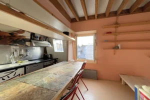 Coin repas et cuisine avec bar carrelé et tabourets, vue dégagée sur les toits parisiens.