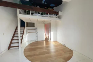 Grande chambre avec mezzanine, poutre apparente et hauteur sous plafond.
