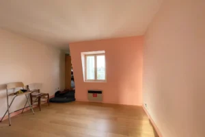 Pièce lumineuse idéale pour chambre ou bureau, murs pastels et parquet bois clair.